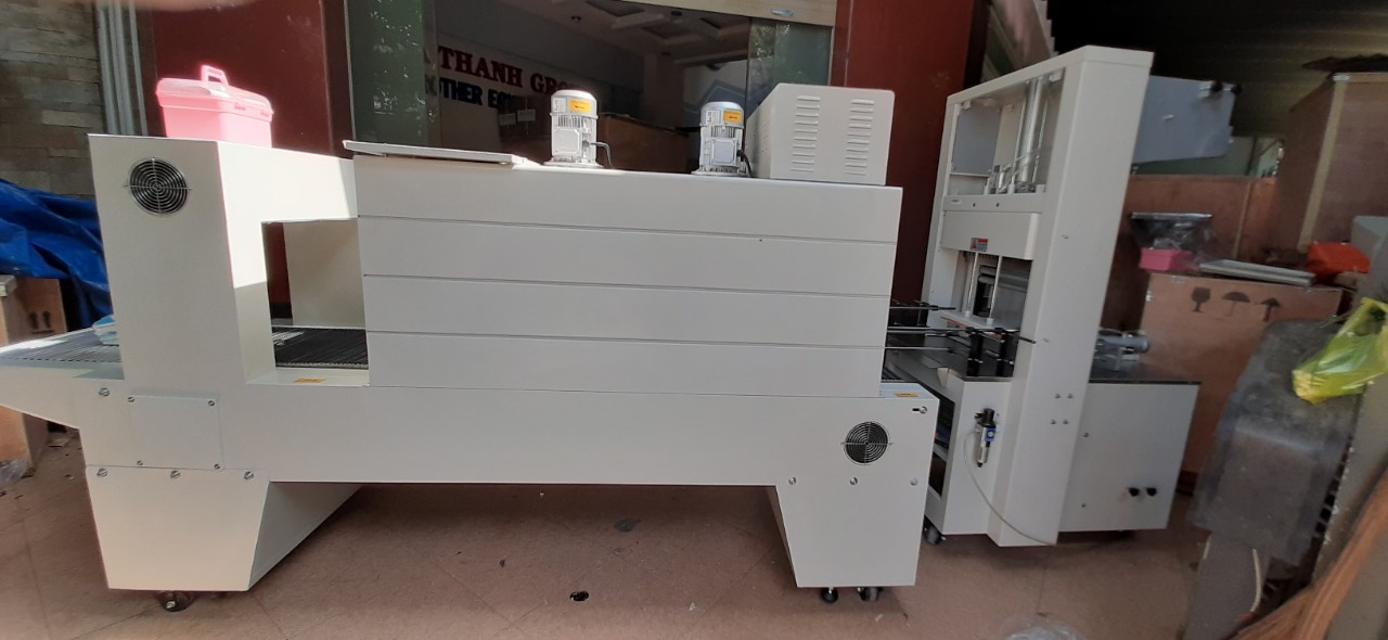 Máy cắt dán và rút màng co lốc chai- lon bán tự động, máy màng co lốc